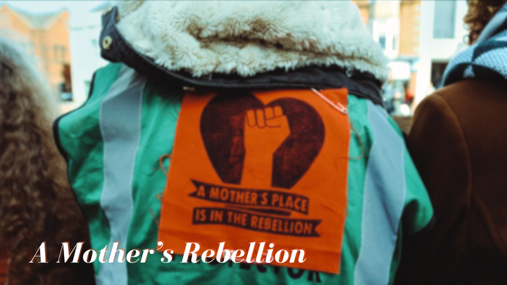 A protestor's back, with Mother's Rebellion banner pinned 