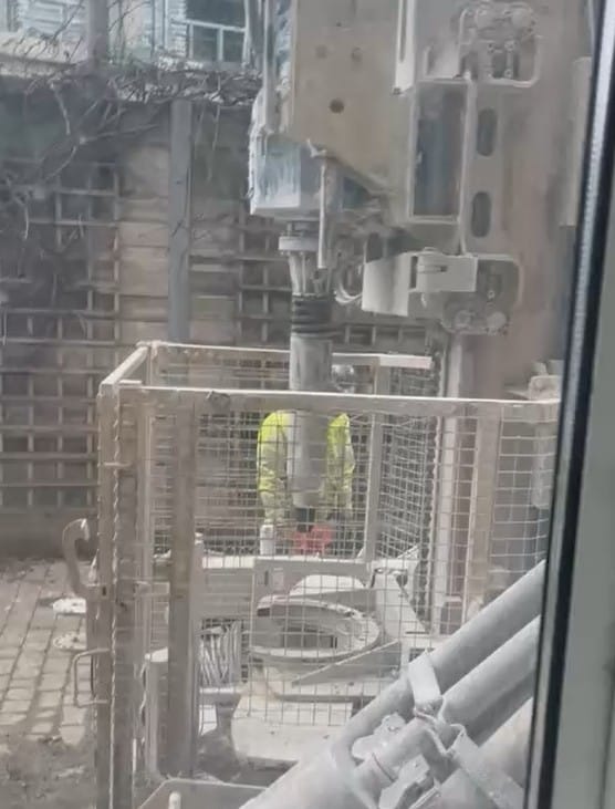 Construction worker with drilling equipment seen through resident's window