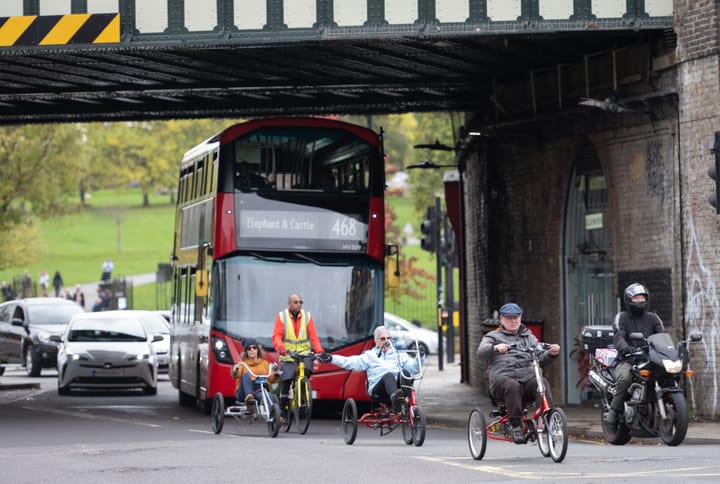 Disabled people using e-assist bikes in traffic at major junction