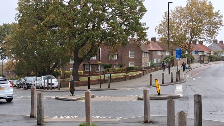 Some red brick houses, grass and trees in the Downham estate, built in 1920s by LCC.