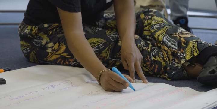 Image from workshop, person sitting on floor and writing on poster.