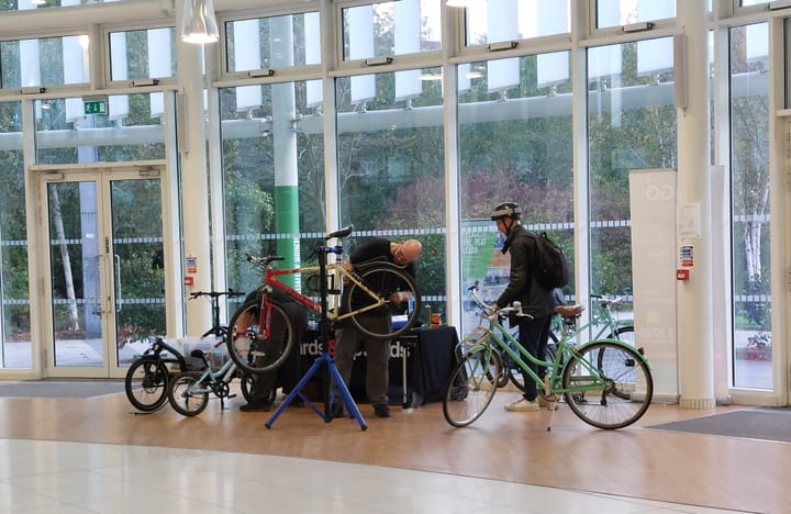 Repair person and cyclist with bike inside Glass Mill atrium.