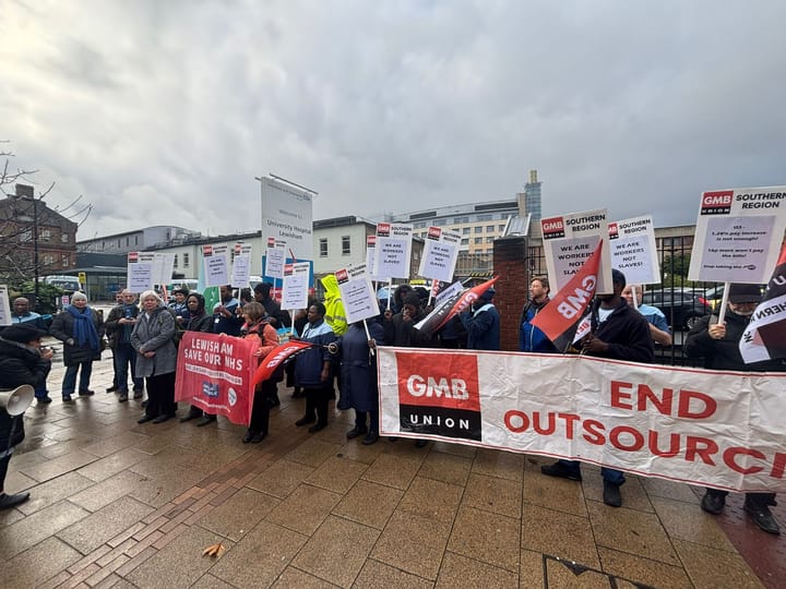 Protestors outside the hospital with signs "GMB Union, End Outsourcing" and placards, "We are workers, not slaves". 