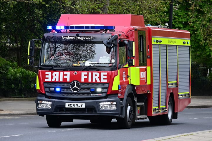 London Fire Brigade truck responding to an emergency, driving down Embankment. 